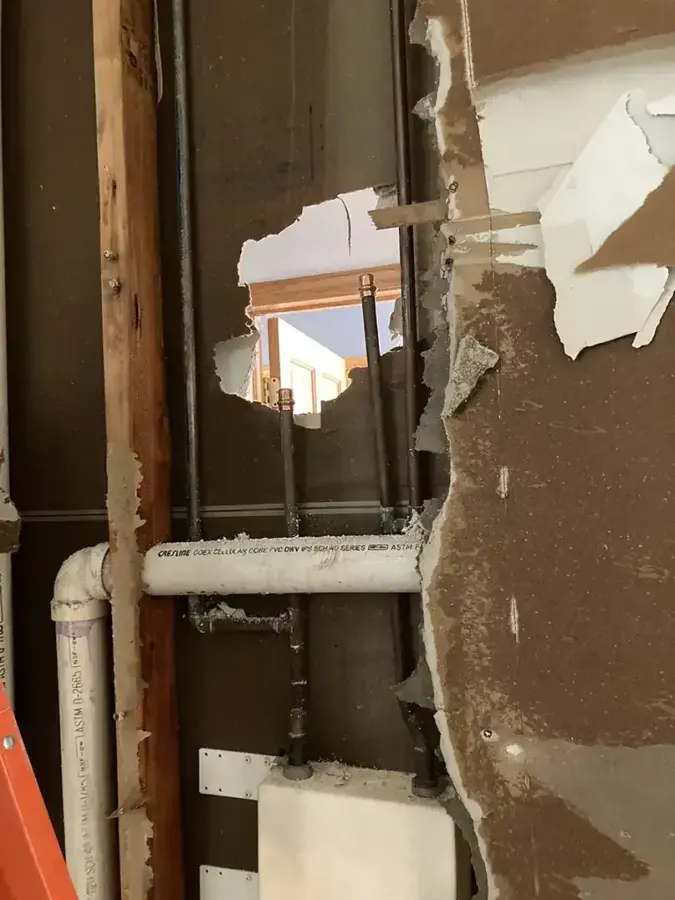Wall opened to reach the supply pipes behind water-damaged drywall