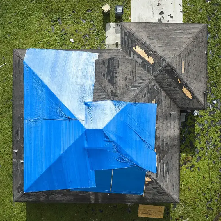 Blue tarp over a storm-damaged shingle roof north of Tampa, seen from above